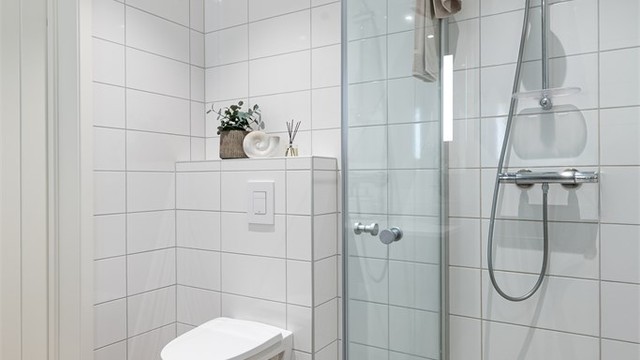 Dusjhjørne med glassdører og vegghengt toalett.