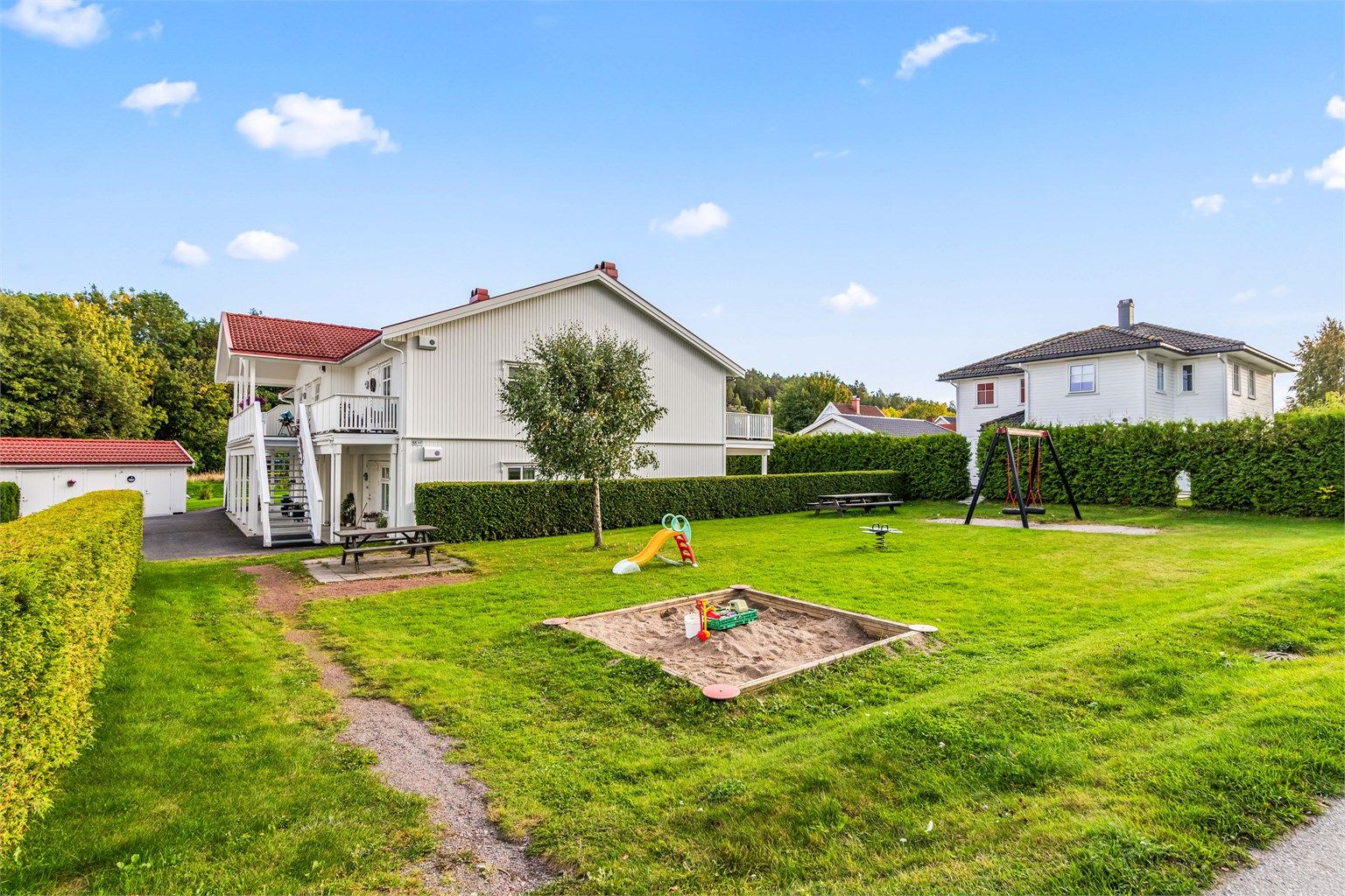 Felles uteområde med gressplen og lekeplass for barna.