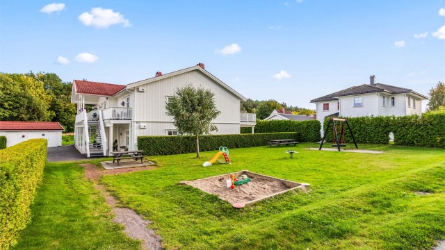 Felles uteområde med gressplen og lekeplass for barna.