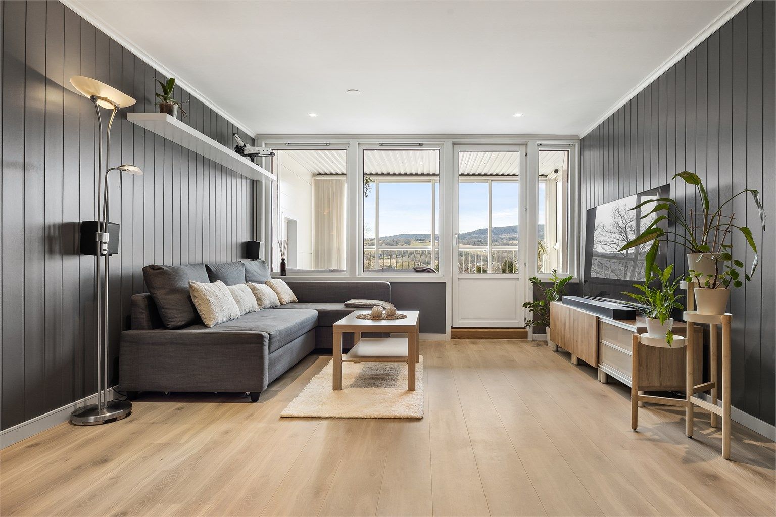 Stuen har gjennomgående laminatgulv og vegger med malte MDF-plater, som gir et helhetlig inntrykk.