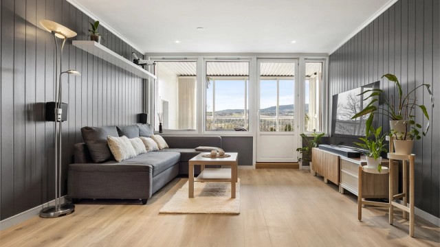 Stuen har gjennomgående laminatgulv og vegger med malte MDF-plater, som gir et helhetlig inntrykk.