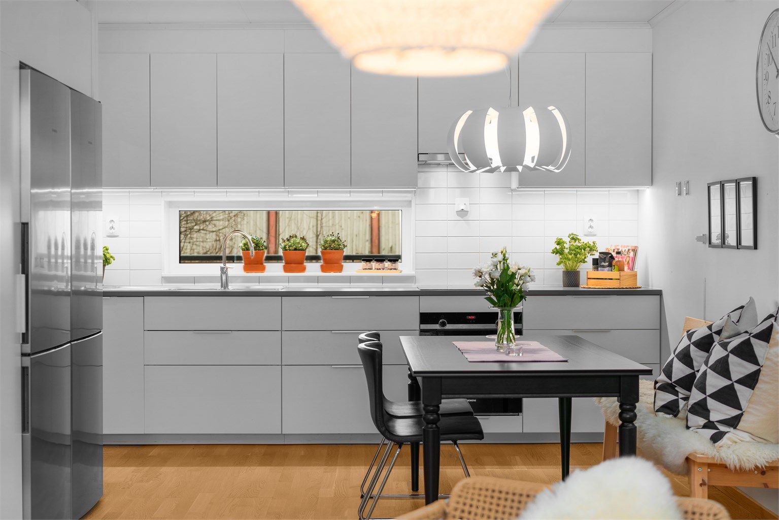 Kjøkkeninnredning fra 2018 med slette, hvite fronter, laminatbenkeplate og integrerte hvitevarer.