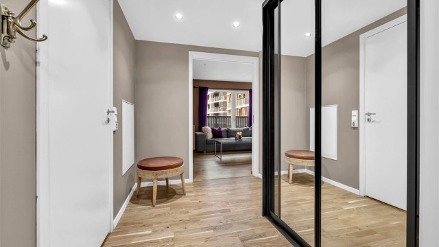 Romslig entrè med skyvedrøsgarderobe, klesopphenging og tilkomst til boligens innvendige bod