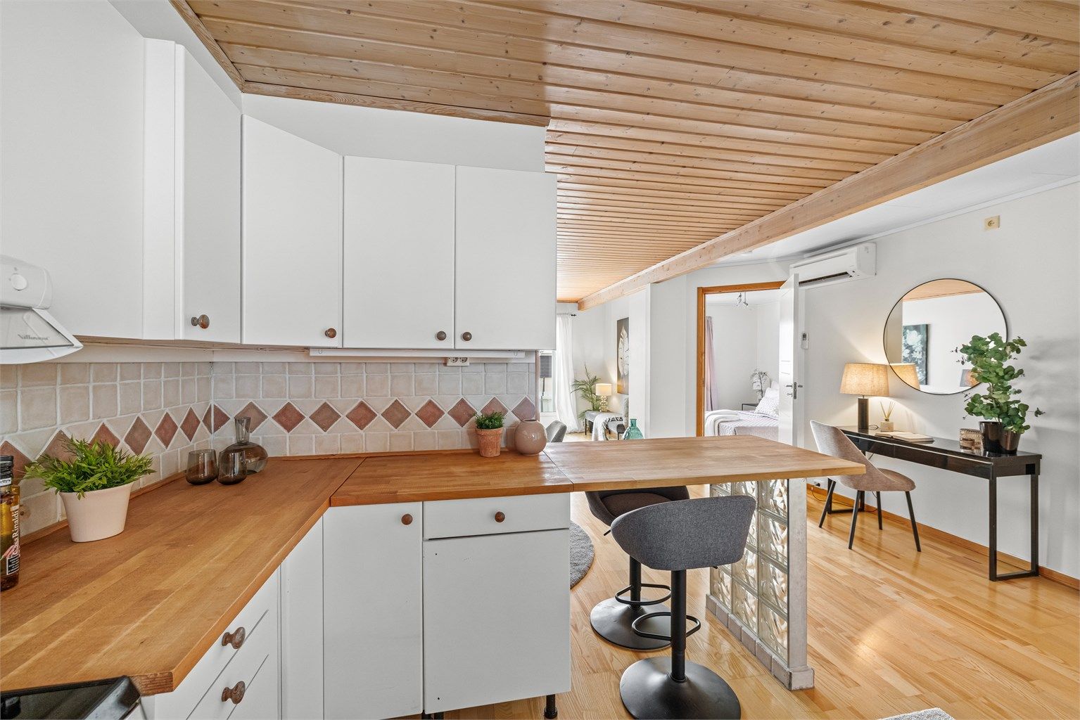 Benkeplaten i heltre gir en varm kontrast til de hvite, glatte frontene på kjøkkeninnredningen.