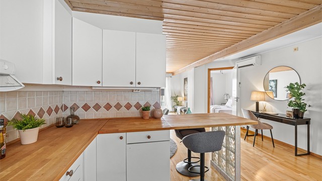 Benkeplaten i heltre gir en varm kontrast til de hvite, glatte frontene på kjøkkeninnredningen.