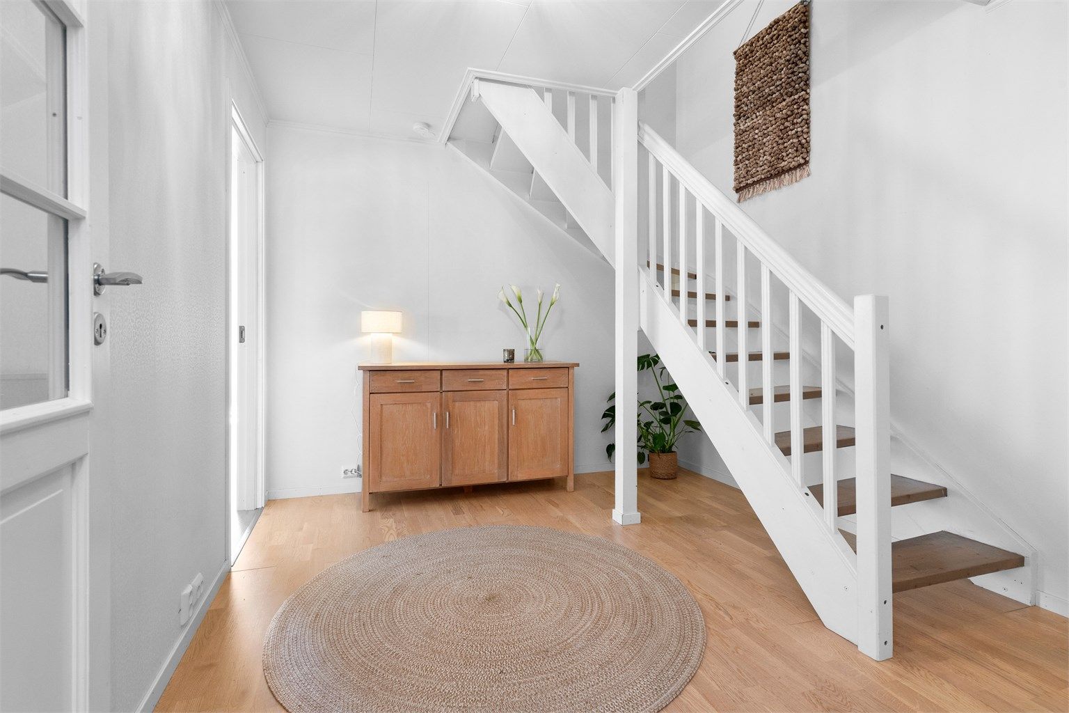 Hallen binder sammen rommene i første etasje og har en malt innvendig tretrapp fra byggeåret