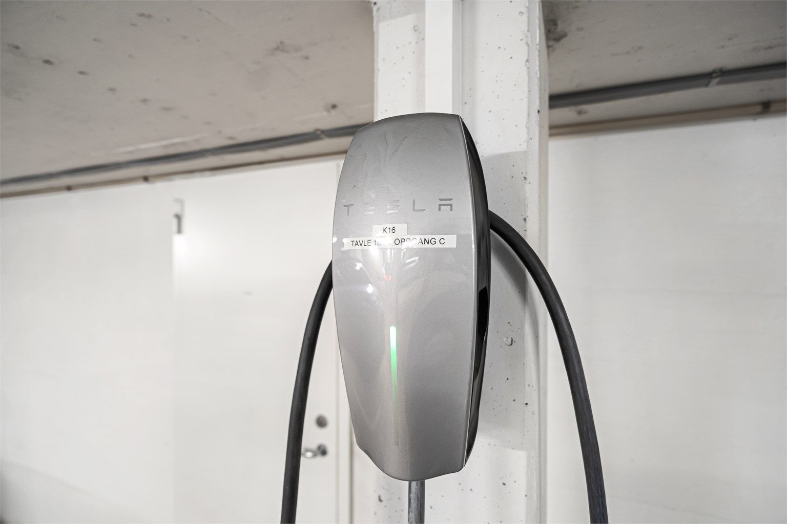 Tesla el-bil lader medfølger, svært praktisk med bod på hele 7 kvm i bakkant av parkeringsplassen