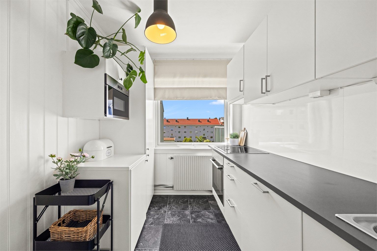 Kjøkkeninnredning med glatte fronter og slitesterk laminatbenkeplate. Vaskemaskin er praktisk plassert i eget skap på kjøkkenet.