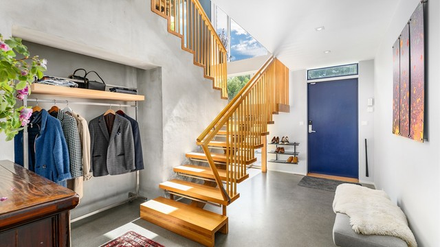 Den store entreen/hallen med gulv av slipt betong er et meget representativt første møte med boligens indre. Arkitekttegnet trapp i massiv eik.