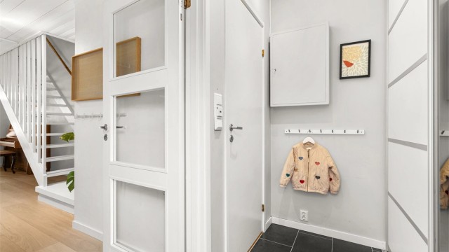 Entré med gulvfliser med varmekabler og praktisk skyvedørsgarderobe med god plass til yttertøy