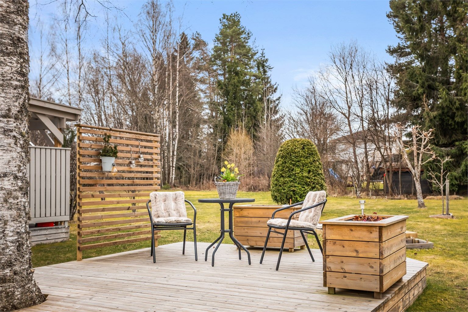 Tomten er pent opparbeidet med plen, beplantning og flere uteplasser.