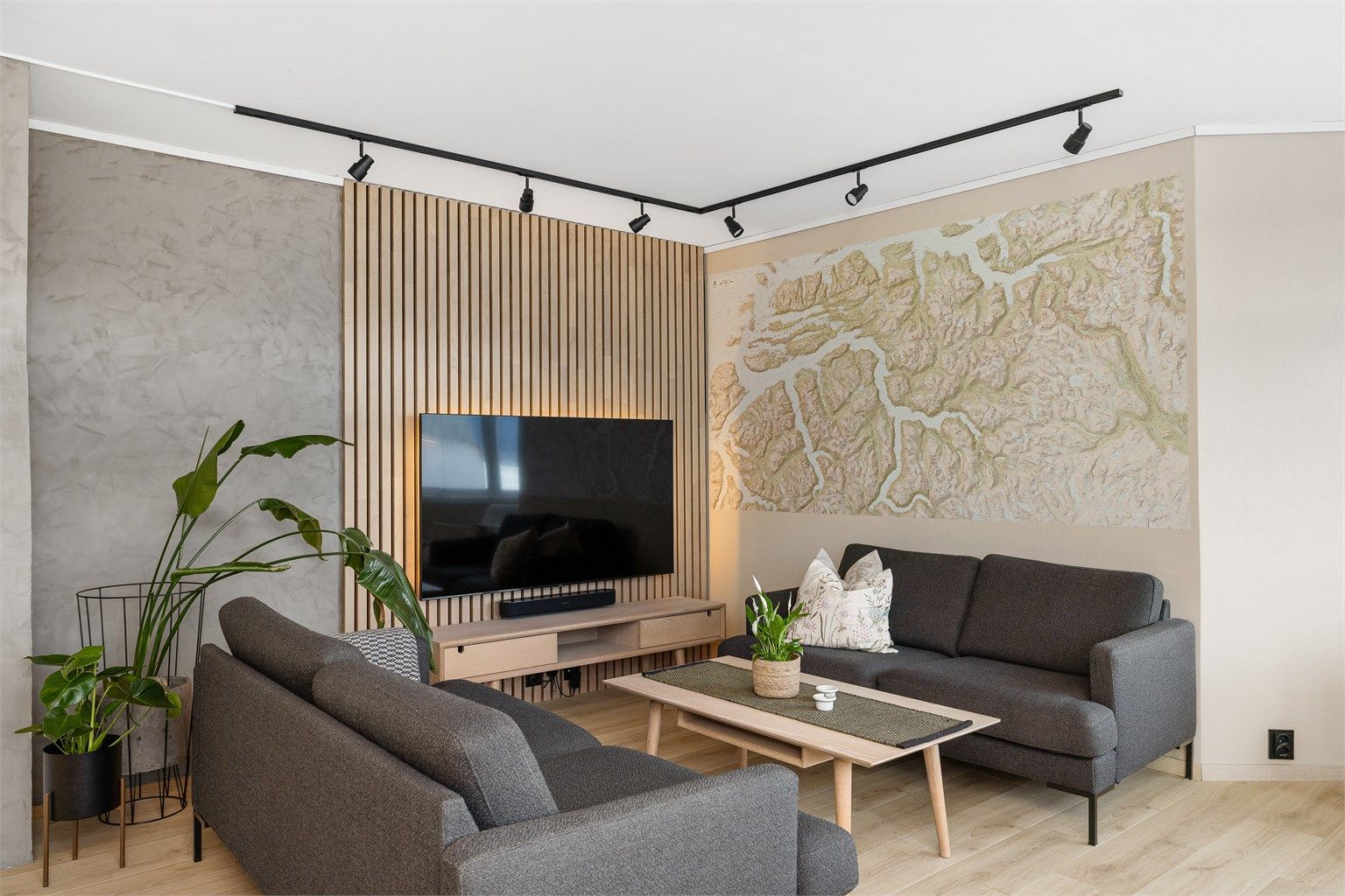 Rommets størrelse gir mulighet for å innrede i soner. I dag er stuedelen innredet med tv-sone. Legg merke til den sorte spotskinnen og sorte stikkontakter som forsterker et modernisert preg