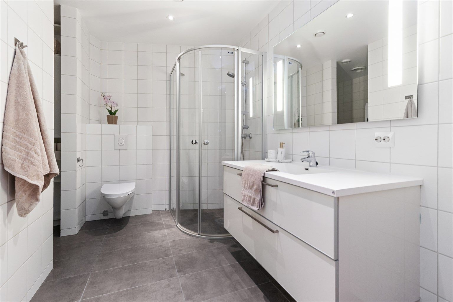 Flislagt bad i 1. etasje med praktisk innhugg til vaskemaskin og oppbevaring.