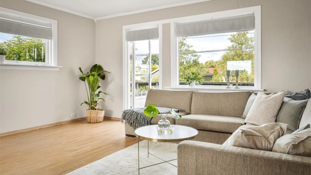 Lys stue med sofaområde og spiseplass.