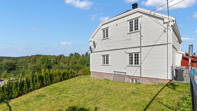 Tomten er opparbeidet med grønn plen omkranset av skjermende hekk.