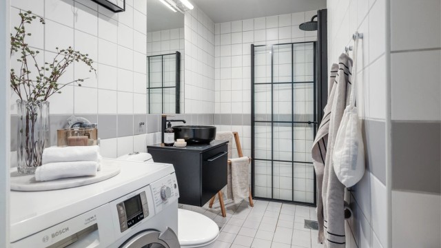 Et stilrent, flislagt bad med gulvvarme og opplegg for vaskemaskin, praktisk tilrettelagt for en komfortabel hverdag.