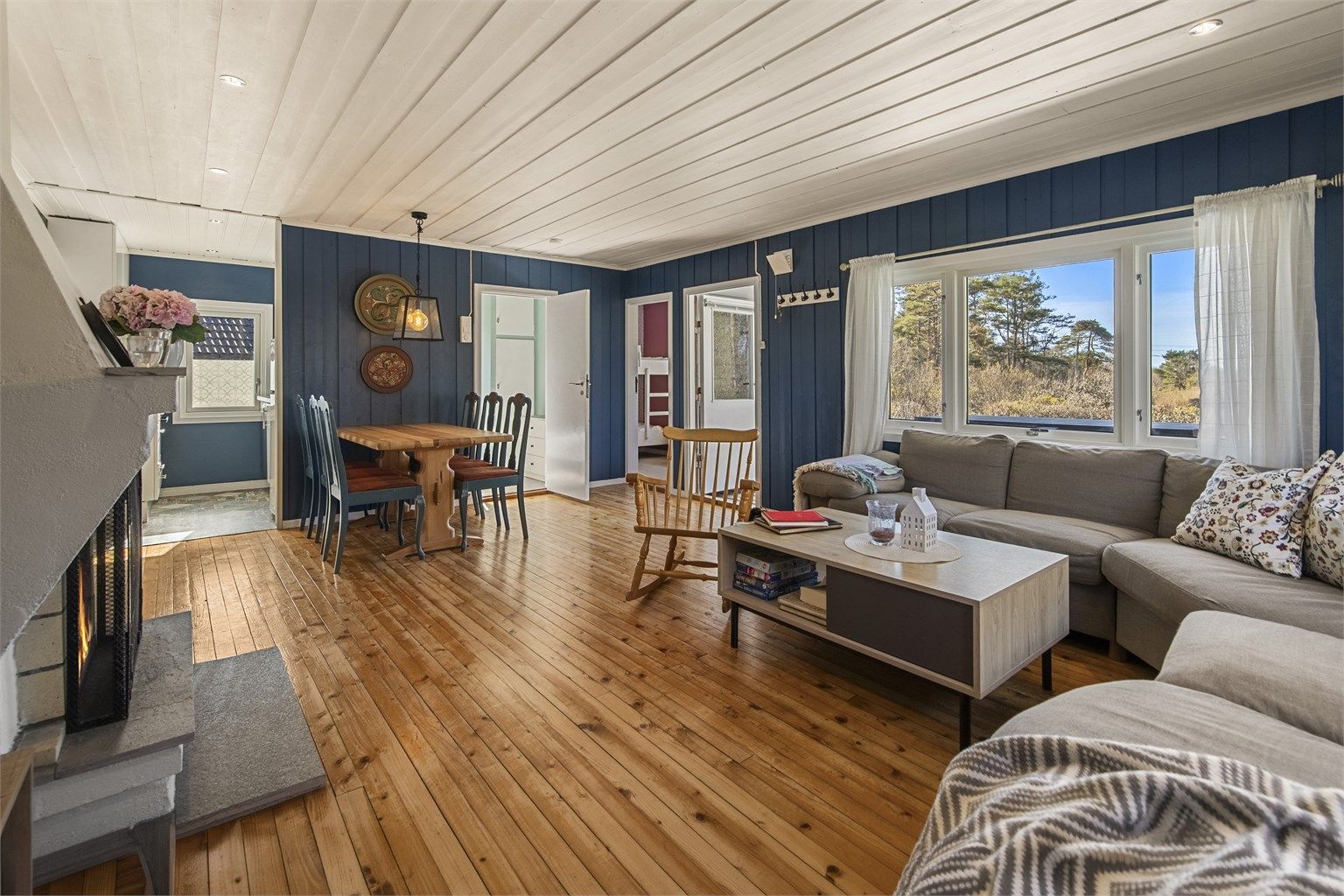 Vegger er malt i sommerlige fargevalg. De store vinduer skaper en lys og trivelig atmosfære i stuen.