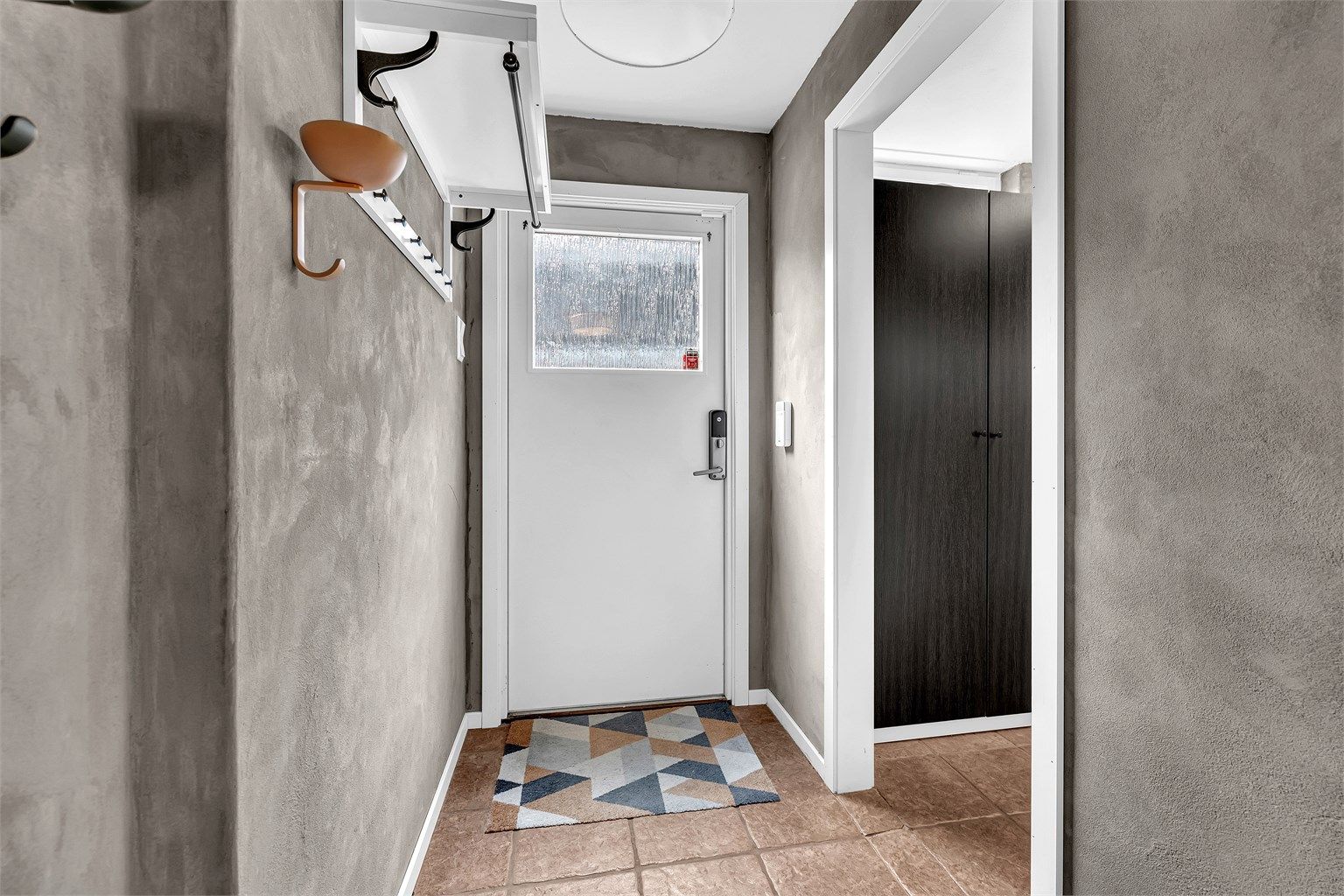 Boligen ønsker deg velkommen inn i en fin entrè med kalkmaling på vegger og fliser med gulvvarme i boligens underetasje. 