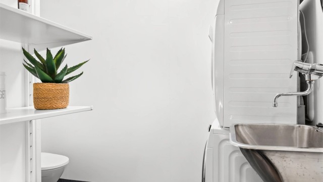 Praktisk vaskerom med gulvmontert toalett, utslagsvask og opplegg for vaskemaskin.