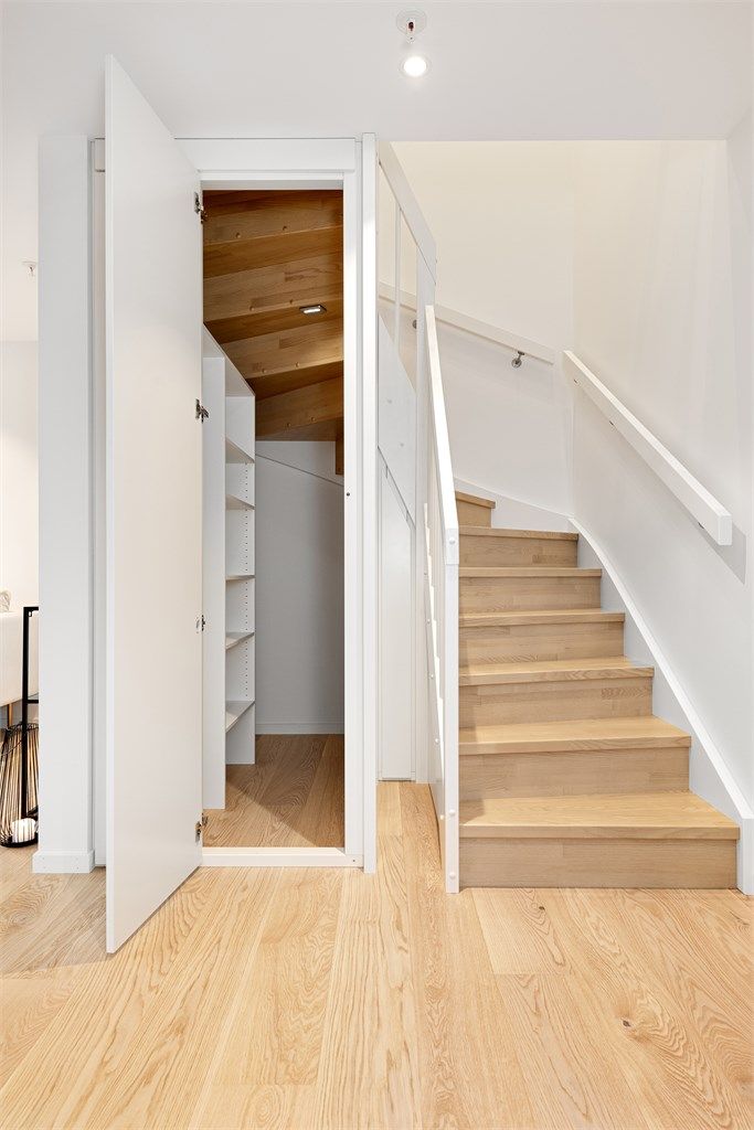 Under trappen er det en smart utnyttet bod med praktiske hyller for lagring.