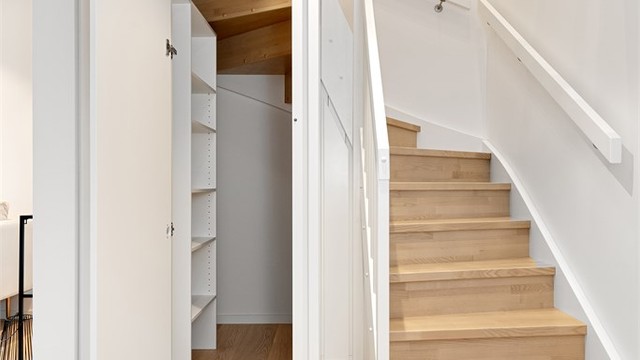 Under trappen er det en smart utnyttet bod med praktiske hyller for lagring.