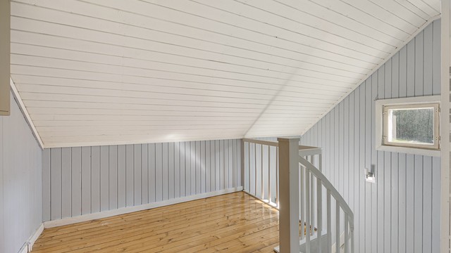 Trappegang i loftsetasjen med heltre gulv og panelte overflater.