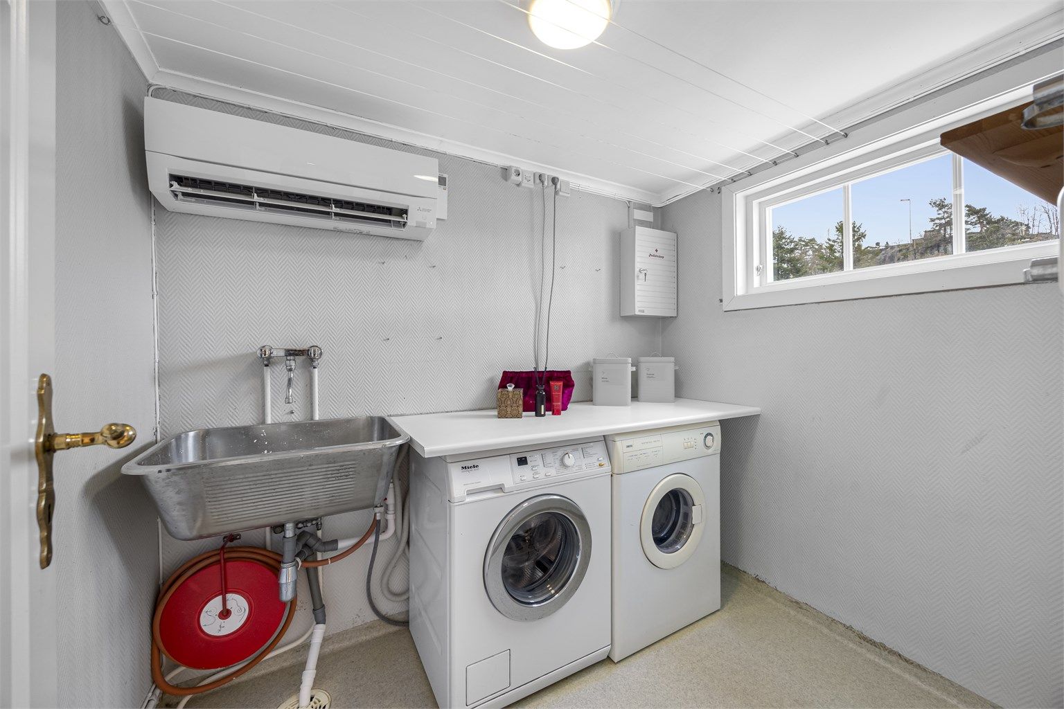Vaskerom med varmepumpe, klesstørkesnorer og plass til vaskemaskin og tørketrommel, samt utslagsvask.