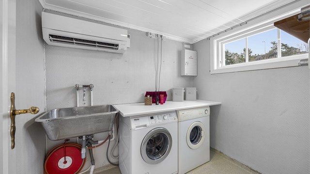 Vaskerom med varmepumpe, klesstørkesnorer og plass til vaskemaskin og tørketrommel, samt utslagsvask.