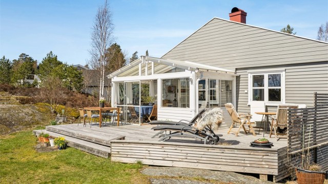 Romslig terrasse i trekonstruksjoner med tilknyttet innglasset utestue.
Foto: Efkt