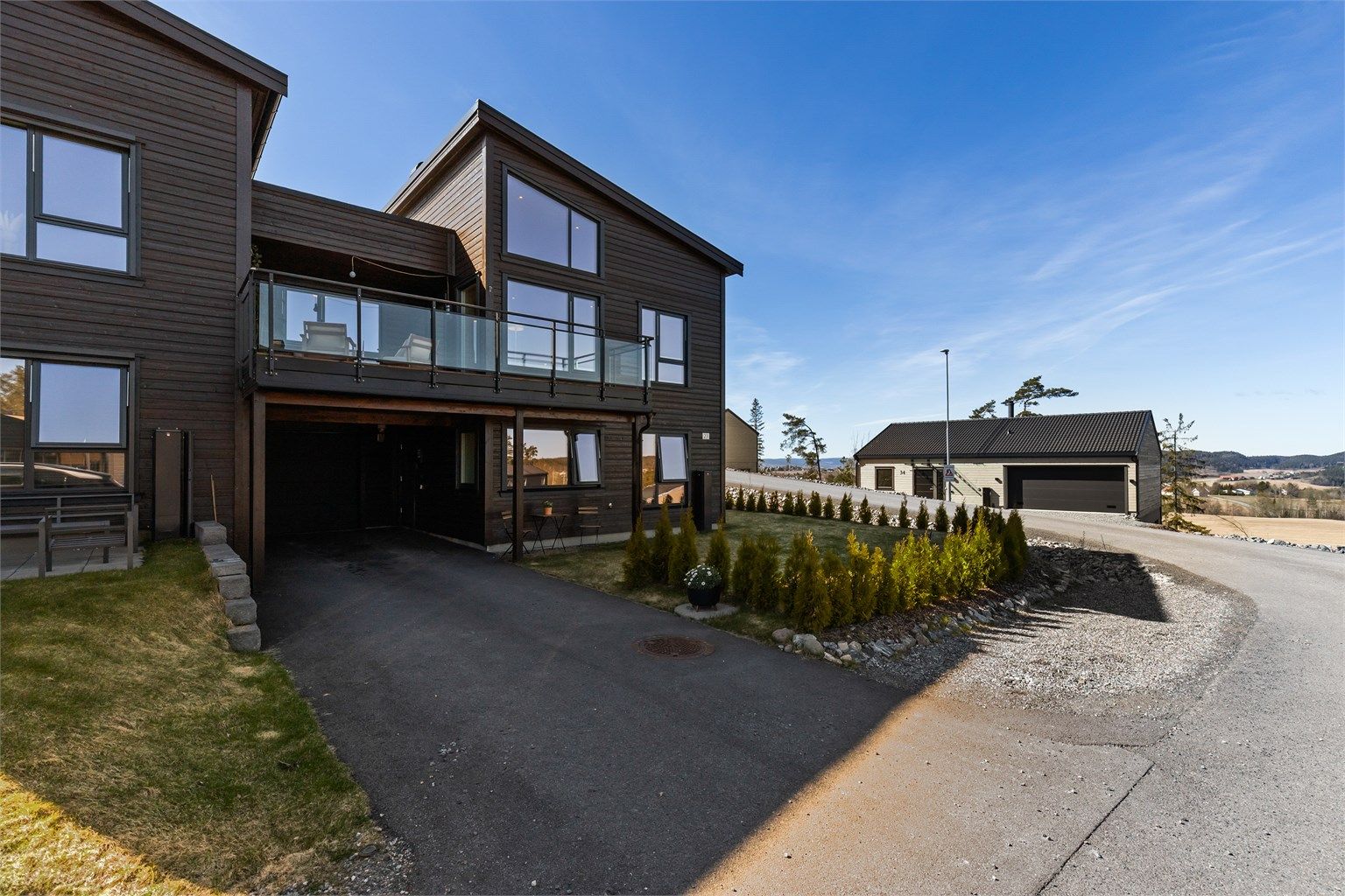 Asfaltert innkjørsel med parkering i carport og garasje, samt plass til flere biler utendørs.