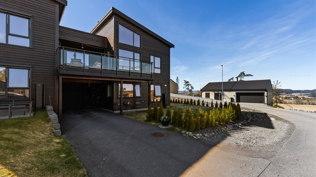 Asfaltert innkjørsel med parkering i carport og garasje, samt plass til flere biler utendørs.