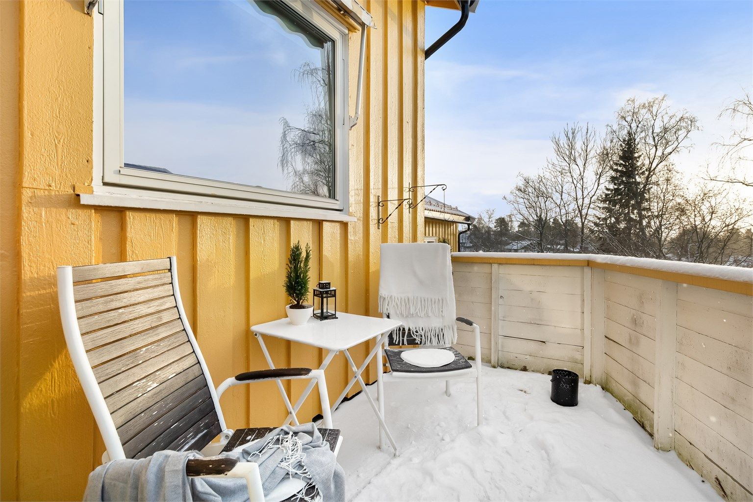 Rekkverket i treverk rammer inn uteplassen.