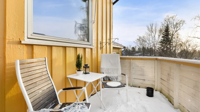 Rekkverket i treverk rammer inn uteplassen.