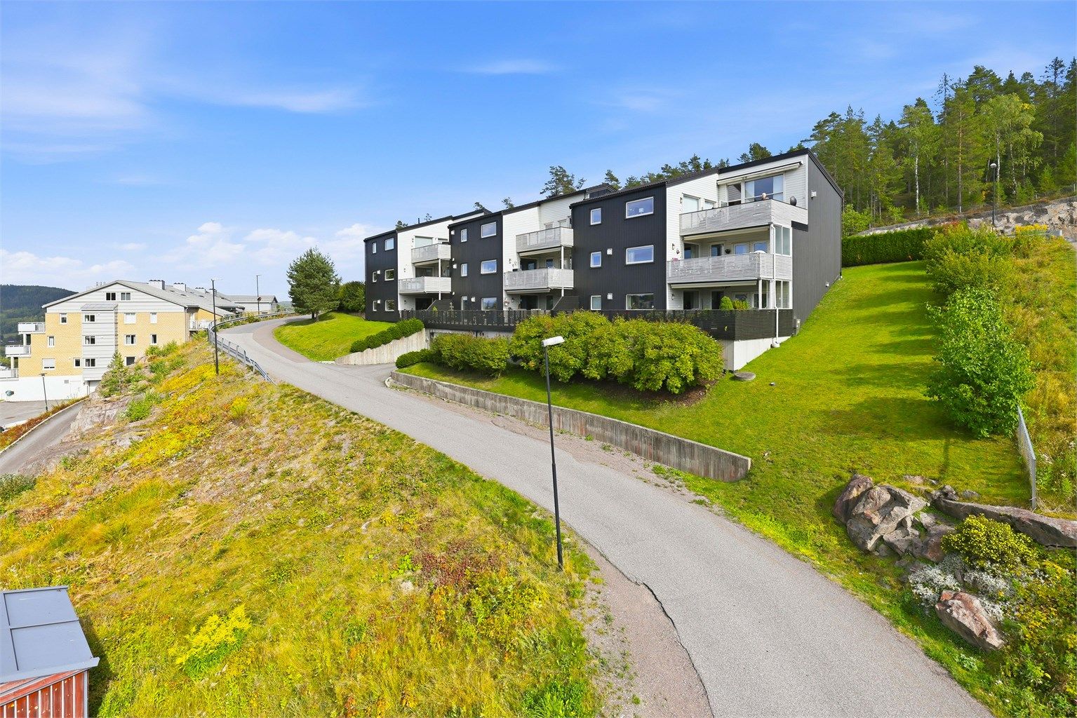 Sameiet har en pent opparbeidet skrånende tomt med plen og beplantninger og praktiske støttemurer