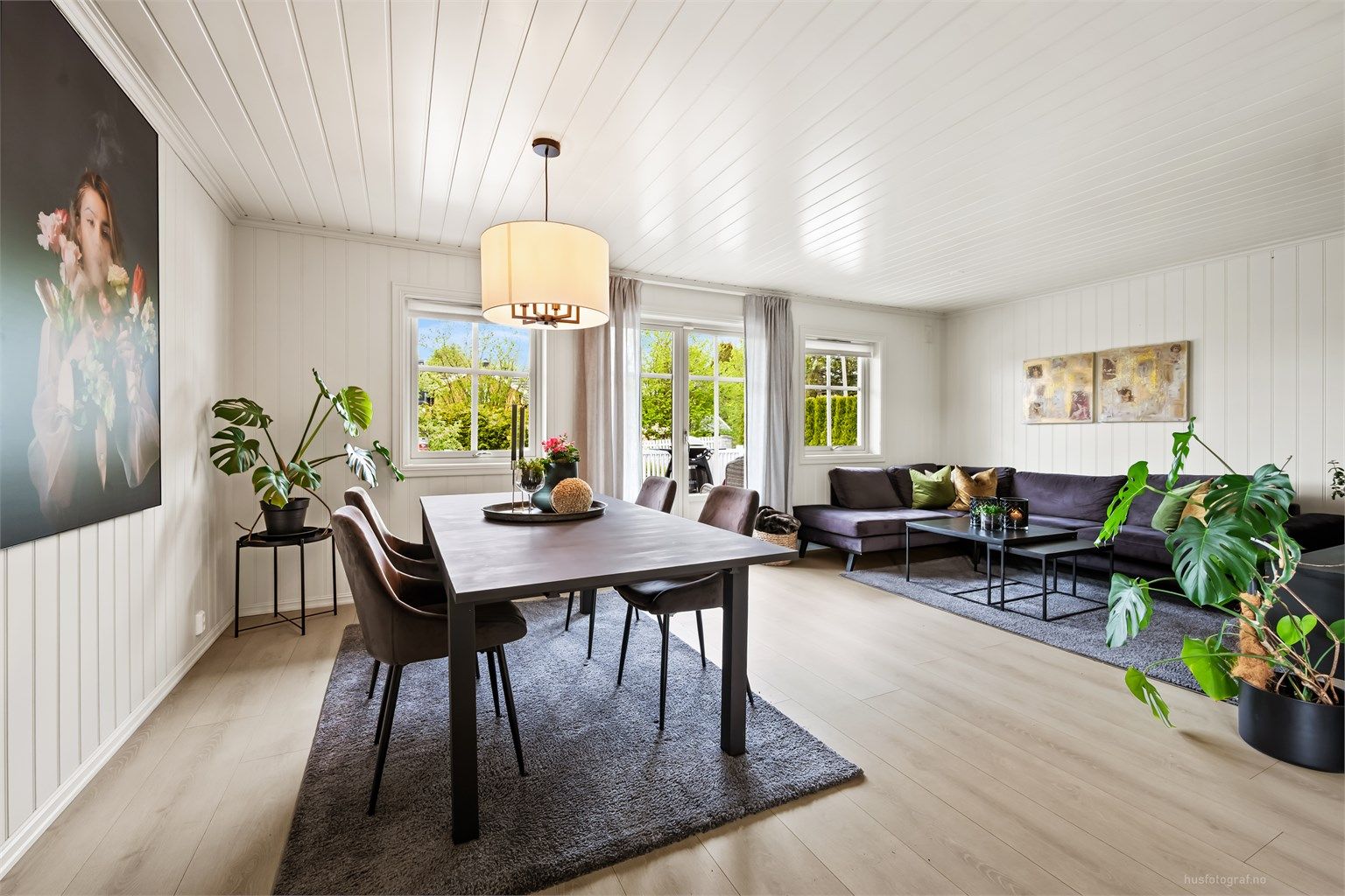 Romslig vinkelstue med sofaområde, spiseplass og sittegruppe.