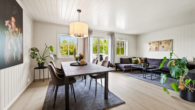 Romslig vinkelstue med sofaområde, spiseplass og sittegruppe.