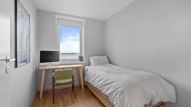 Soverom I med plass til stor seng og nattbord. Vegger malt i en dus og fin farge, parkett på gulv. Nydelig sjøutsikt.