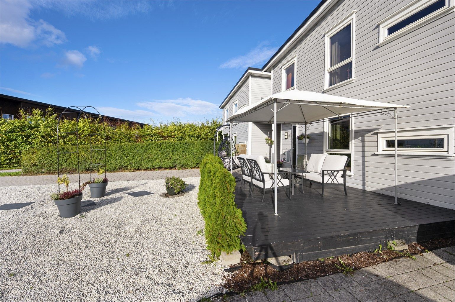 Blåklokkesvingen 27 - Enebolig i kjede over to plan med carport og opparbeidede uteplasser på begge sider av boligen.