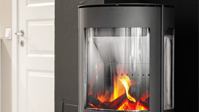 Frittstående peisovn med glassplate på gulv.