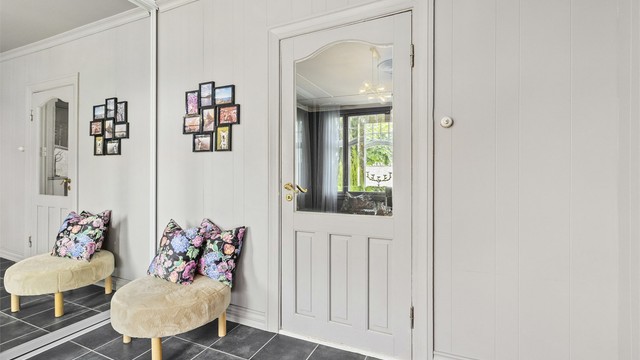 Romslig flislagt gang med spesialbygd skyvedørsgarderobe.
