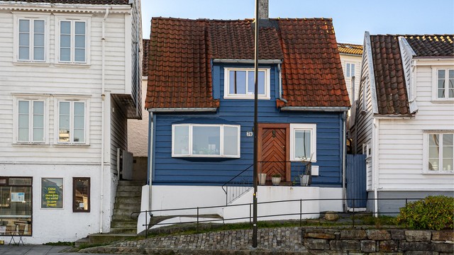 Inngangsparti med steintrapp og smijernsrekkverk mot gaten.