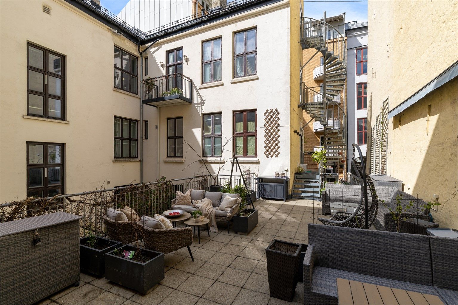 Stor felles takterrasse med flere sittegrupper og diverse plantekasser