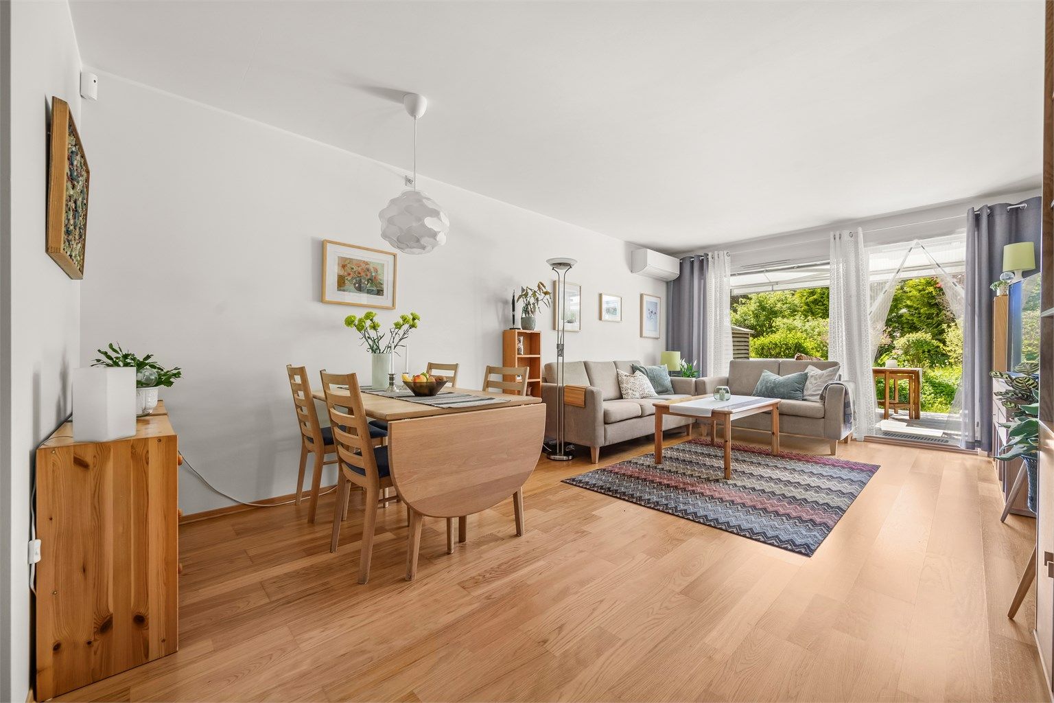 Lys og romslig stue med god plass til både spisebord og sittegruppe, varmepumpe fra 2023 og direkte utgang til den solrike terrassen. Foto: Martine Eren Jacobsen