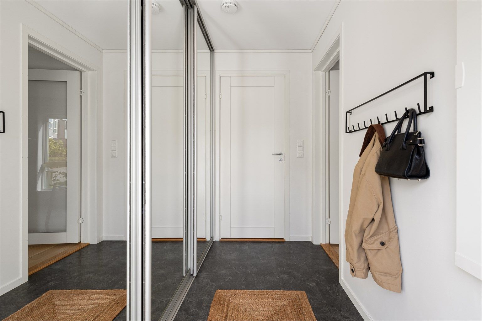 Entréen har laminatfliser på gulv og romslig skyvedørsgarderobe med speilfronter.