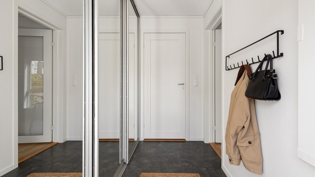 Entréen har laminatfliser på gulv og romslig skyvedørsgarderobe med speilfronter.