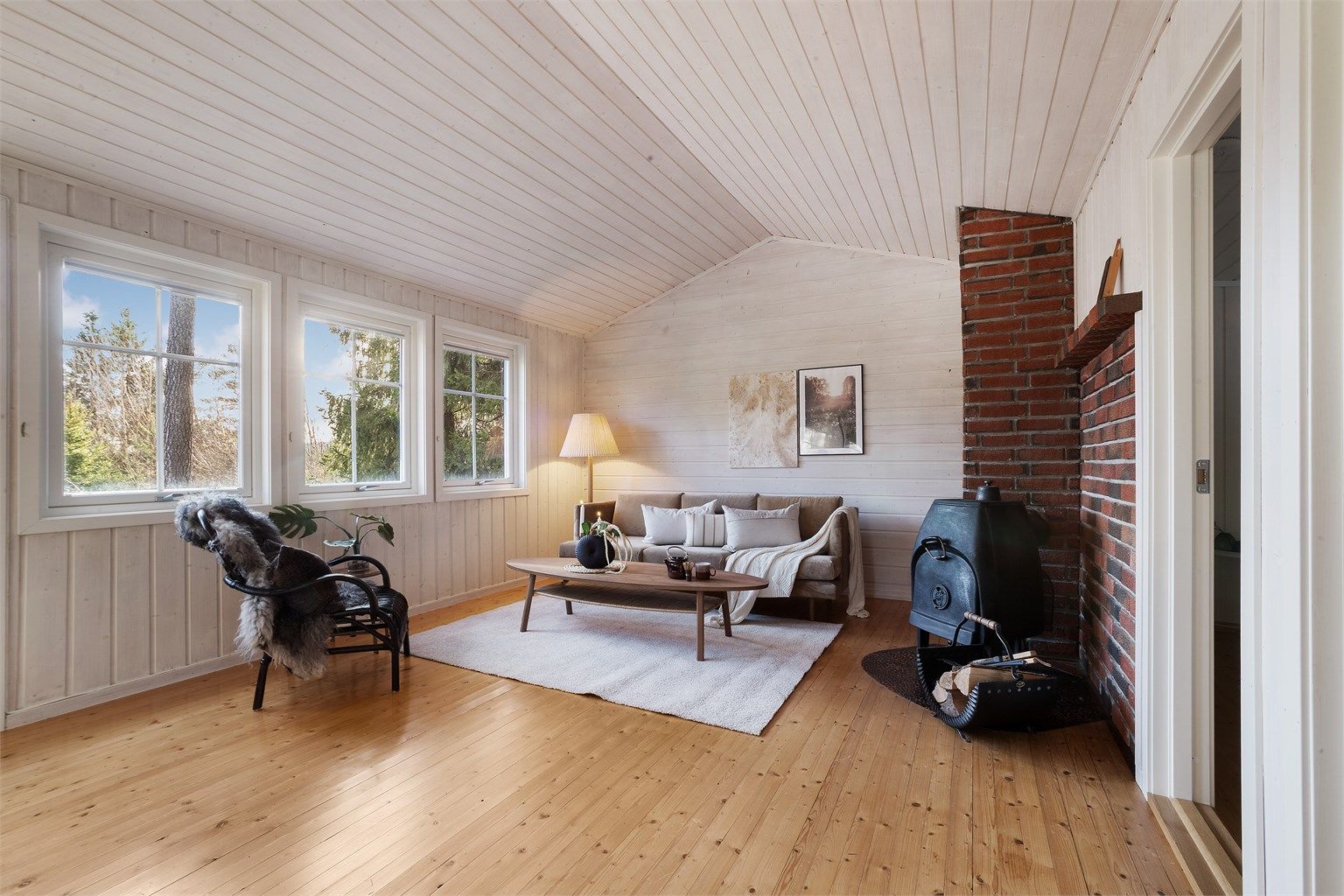 Stuen er et lyst samlingspunkt. Vedovnen i støpejern gir varme og skaper en lun atmosfære.