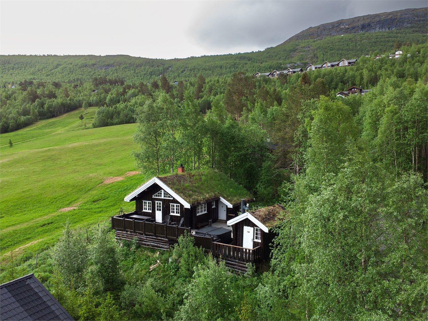 Fritidsboligen ligger fint til i terrenget med tradisjonelt torvtak.