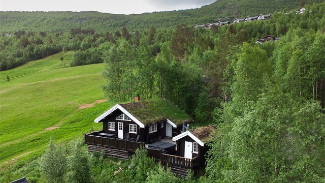 Fritidsboligen ligger fint til i terrenget med tradisjonelt torvtak.