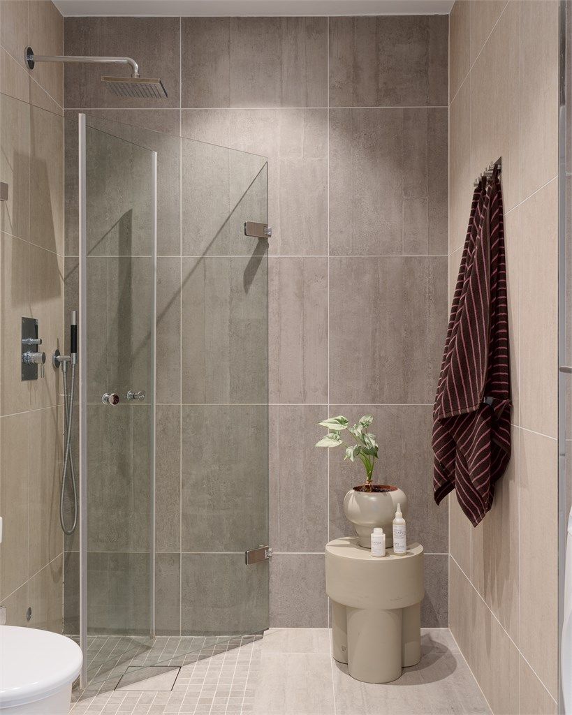 Dusjhjørne med innfellbare glassdører og regndusj. I himlingen er det integrerte høyttalere og i gulvet er det varmekabler.