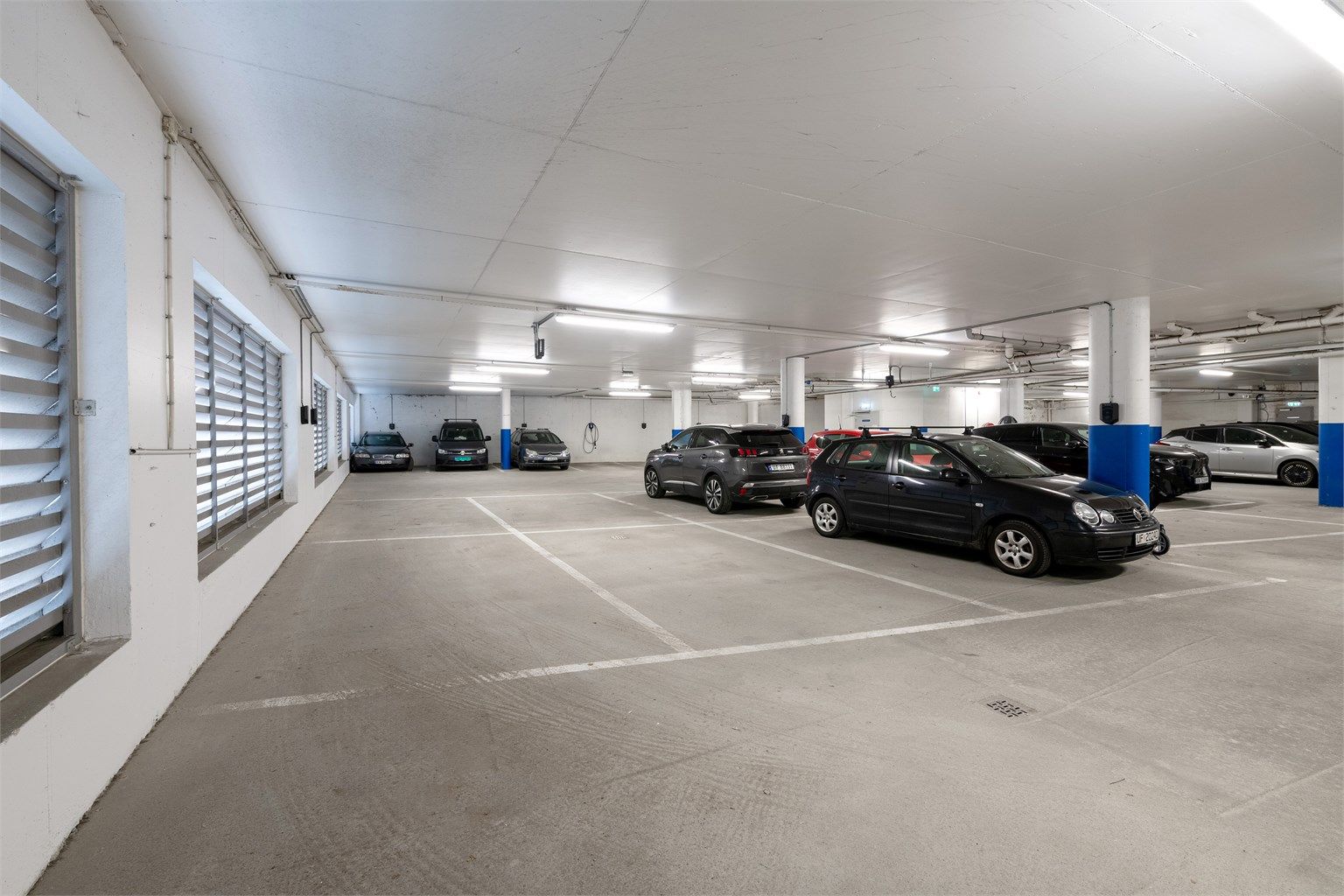 Fast biloppstillingsplass med elbillader i byggets lukkede garasjeanlegg.